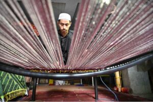 A young worker busy in weaving traditional bed (Charpai) at his workplace in Dabgari area.