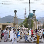 A large crowd gathers at the main entry gate of Shrine Bari Imam in the Federal Capital