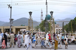 A large crowd gathers at the main entry gate of Shrine Bari Imam in the Federal Capital