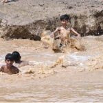 Children enjoying bath in the rain water accumulated in water pond in the Federal Capital