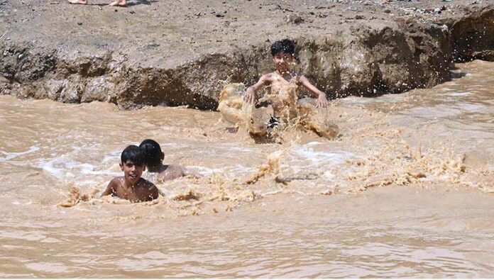Children enjoying bath in the rain water accumulated in water pond in the Federal Capital
