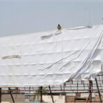 Laborers fixing a huge advertisement banner on a billboard without safety measures at Chungi No 09