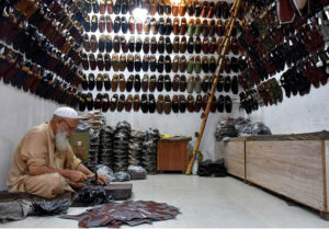 A cobbler preparing traditional shoes (Peshawari Chappal) to the customers at his workplace