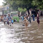 Motorcyclists and auto rickshaw passing through rain water accumulated on road after rain in the Provincial Capital