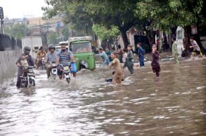Motorcyclists and auto rickshaw passing through rain water accumulated on road after rain in the Provincial Capital