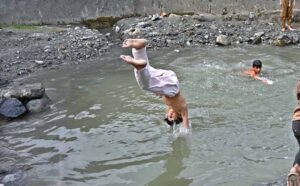 Youngsters jumping and bathing in water pound to get relief from hot weather in city.