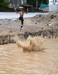 Children enjoying bath in the rain water accumulated in water pond in the Federal Capital