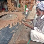 An old man busy in making a beautiful handmade wooden mirror frame at his roadside setup in the city