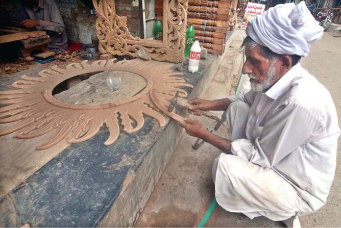 An old man busy in making a beautiful handmade wooden mirror frame at his roadside setup in the city