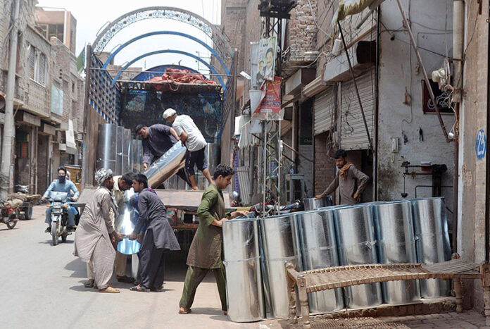 Laborers are loading iron sheets on truck at Loha Market
