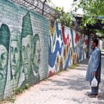 A person looking the portraits of Quaid-e-Azam Muhammad Ali Jinnah, Allama Muhammad Iqbal, Fatima Jinnah and Sir Syed Ahmad Khan on a wall at F-6 in the Federal Capital