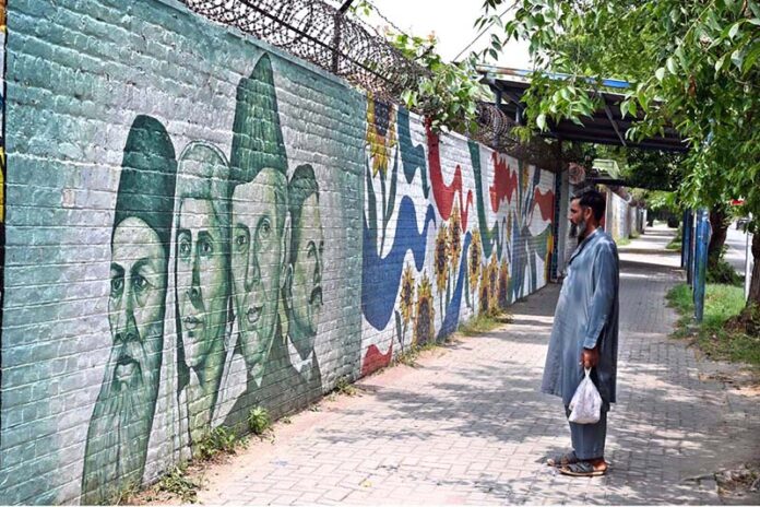 A person looking the portraits of Quaid-e-Azam Muhammad Ali Jinnah, Allama Muhammad Iqbal, Fatima Jinnah and Sir Syed Ahmad Khan on a wall at F-6 in the Federal Capital