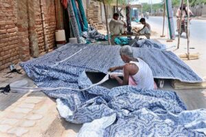 A skilled artisan deftly weaves traditional curtains panels "chicks" with bamboo sticks and fabric at their workshop .