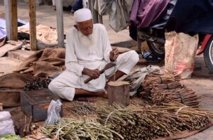 An elder vendor is preparing traditional tooth brush (Miswak) at clock tower chowk.