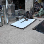 Workers busy in preparing huge iron containers for the storage of wheat to the customers at their workplace