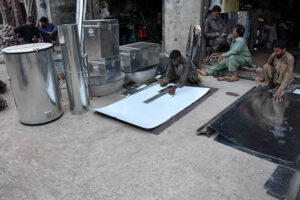 Workers busy in preparing huge iron containers for the storage of wheat to the customers at their workplace