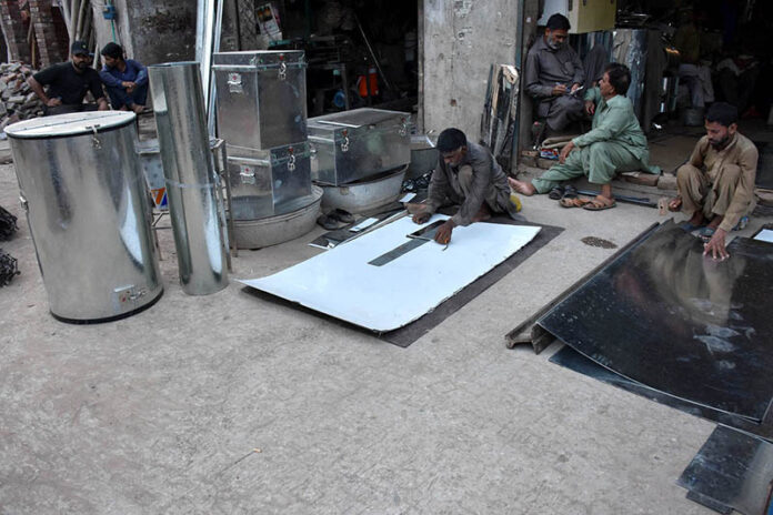 Workers busy in preparing huge iron containers for the storage of wheat to the customers at their workplace