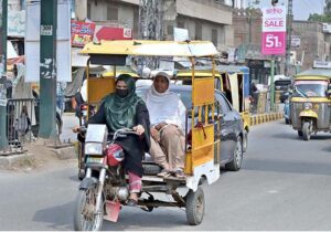 A woman driver rides a rickshaw on a busy city road, earning a livelihood to support her family.