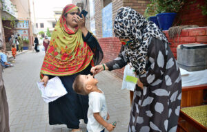 Lady Health worker administering polio drops to a child during anti polio campaign door to door “Polio Free Pakistan” in the city.