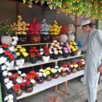 A vendor arranging and displaying artificial flower to attract the customers outside weekly Sunday Bazaar setup in H-9 Sector in Federal Capital