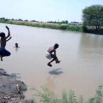 Youngsters jumping and bathing in a Canal to get some relief from scorching hot and humid weather in the city
