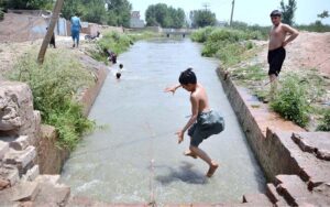 Youngsters find relief from scorching temperatures by jumping into a canal for swim in the city