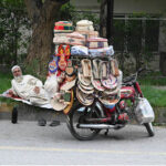 An elder vendor displaying handmade items at roadside in the Federal