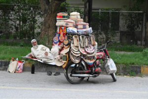 An elder vendor displaying handmade items at roadside in the Federal