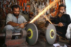 Blacksmith busy in sharpening knives to be used during the procession of Muharram at Kohati area.