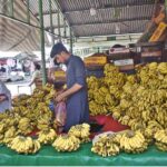 A vendor selling bananas to customers at his stall in weekly Sunday Bazaar in the Federal Capital