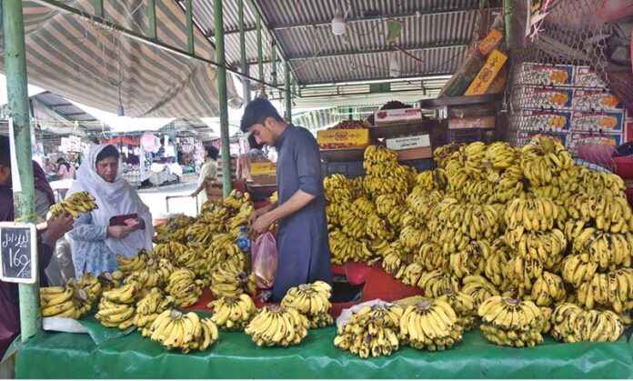 A vendor selling bananas to customers at his stall in weekly Sunday Bazaar in the Federal Capital