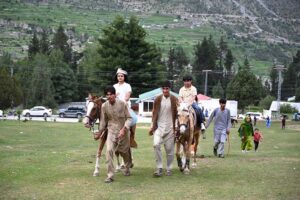 A woman tourist enjoying horse ride at Nalter Valley, a popular tourist destination, as a large number of other people have also arrived to visit the area