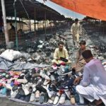 People selecting and purchasing shoes from a makeshift stall at H-9 weekly bazaar in Federal Capital