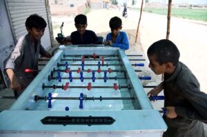 Youngsters playing board football game near Bakapur Village Road.