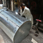 A skilled wielder busy in wielding a big grains storage drum at his work place at goods Naka road in the city