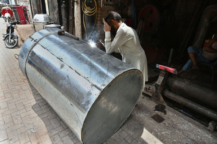 A skilled wielder busy in wielding a big grains storage drum at his work place at goods Naka road in the city