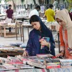 Girls busy in selecting and purchasing old books from roadside stall at Mall Road in Provincial Capital