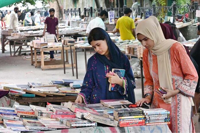 Girls busy in selecting and purchasing old books from roadside stall at Mall Road in Provincial Capital