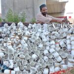A vendor is busy displaying tea cups at roadside setup to attract the customers