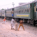 Cricket enthusiasts enjoy the game near the rail track with a passing train