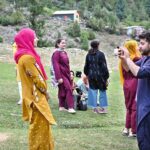 A woman tourist enjoying horse ride at Nalter Valley, a popular tourist destination, as a large number of other people have also arrived to visit the area