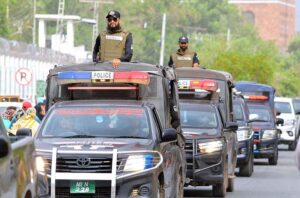 Security officials holding a flag march to develop a sense of protection among the masses and maintain law and order during the holy month of Muharram
