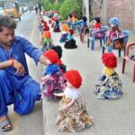 A vendor displaying dolls on footpath along LMQ Road to attract customers