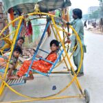Children enjoying the portable swing in the street at Latifabad