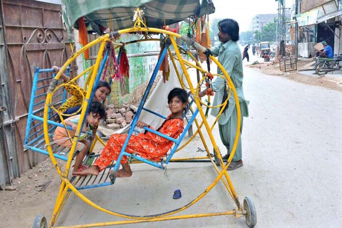 Children enjoying the portable swing in the street at Latifabad