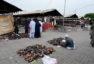 A vendor showcases children's garments at a makeshift stall amidst the debris of last week’s devastating blaze at the H-9 weekly bazaar, which destroyed 2,743 stalls and 625 shops, causing millions in damages in Federal Capital.