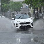 A woman holding an umbrella to protect from rain while riding on motorcycle in the Provincial Capital