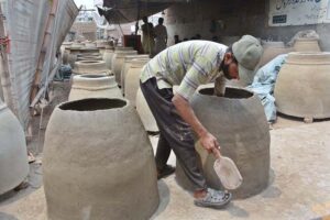 An artisan is giving final touch to the clay ovens (Tandoors) at his workplace Novelty Bridge Samanabad.