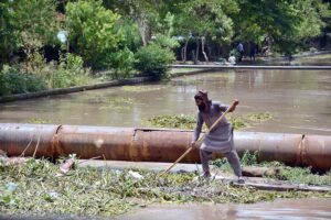 A worker of Irrigation Department cleaning heap of garbage from Rakh Branch Canal.