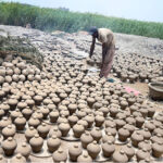 A worker arranging clay-made stuff for draying purpose at his work place at Kumharpara